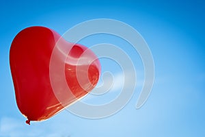 Red ballon - heartshape in the blue sky
