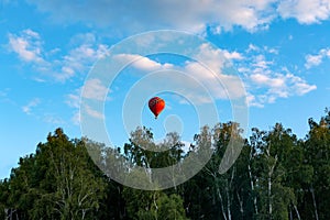 Red balloon flies over the blue clear sky