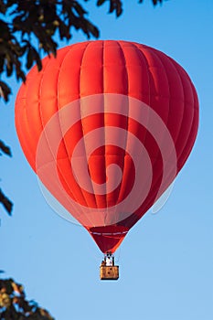 Red balloon in the sky. Aerostat. People in the basket. Fun. Summer entertainment. Romantic adventures