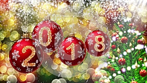 Red balls with numbers 2018 hanging on the background of a bokeh and a rotating Christmas tree.