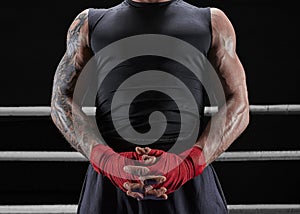 Red bandages on the hands of a kickboxer against the background of the ropes of the ring. The concept of mixed martial arts