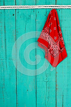 Red bandana hanging by rope border on antique blue wooden background