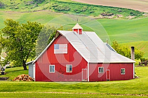 A red barn with an American flag in the Palouse hills