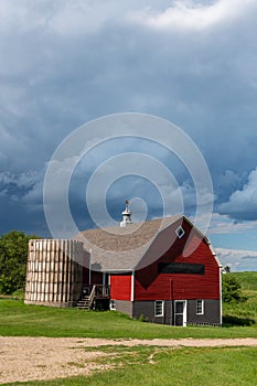 Red barn with brown shingled roof and  old silo on a farm