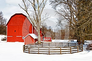 Red barn and circle fence covered in Winter snow