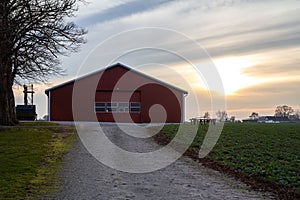 A red barn at the end of a gravel road in a farm landscape in southern Sweden SkÃÂ¥ne, Scania during dusk on a cold winter day