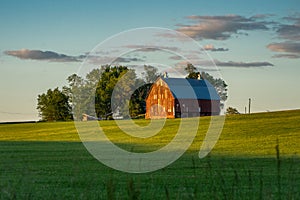 Red Barn in field with clouds and sun