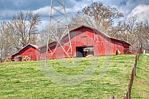 A red barn on a hilltop on a large farm.