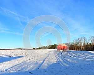 Red barn on snowy winter hill under a blue sky