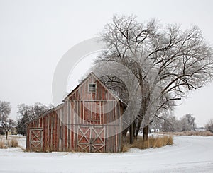 Red barn in winter during snowstorm