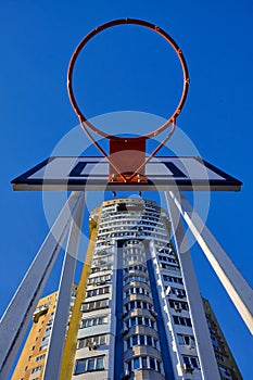 Red basketball hoop in the yard on a background of blue sky.