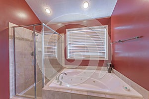 Red bathroom interior with shower stall and drop in bathtub with ceramic tiles surround