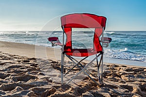 A red beach chair facing the water on Sunset Beach, Hawaii