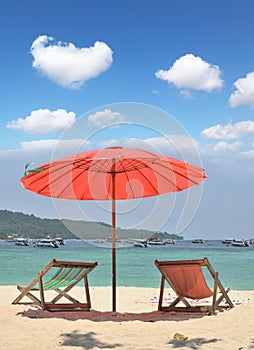 A red beach umbrella and chaise lounges