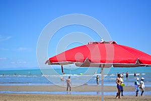 a red beach umbrella colors the beaches of the Adriatic