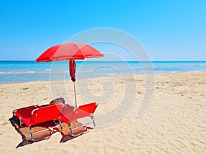 red beach umbrella and deck chairs on the beach