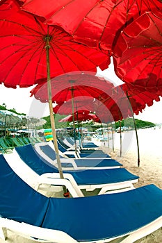 Red beach umbrella and deck chairs on the beach.