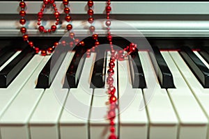 Red beads Christmas decoration lie casually on the piano keyboard