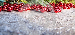 Red beads and conifer branches on a backdrop of rustic wood with snow in sunny day. Background for Christmas and New Year