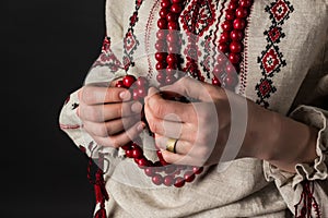 Red beads in hands. Ukrainian embroidery. Rosaries.