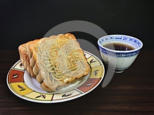 Red bean moon cake served with tea on wooden background .