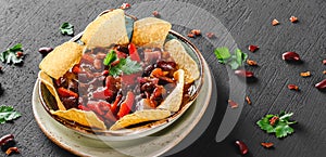 Red bean with nachos or pita chips, pepper and greens on plate over dark background. Mexican snack, Vegetarian food, top view,