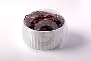 Red beans in a white ceramic cup on a white background