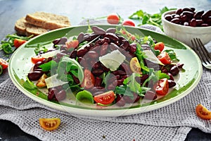 Red beans and wild rocket healthy salad with cherry tomatoes, sea salt flakes and parmesan shavings drizzled with olive