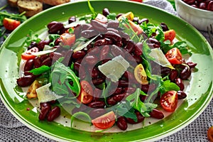 Red beans and wild rocket healthy salad with cherry tomatoes, sea salt flakes and parmesan shavings drizzled with olive