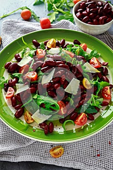 Red beans and wild rocket healthy salad with cherry tomatoes, sea salt flakes and parmesan shavings drizzled with olive