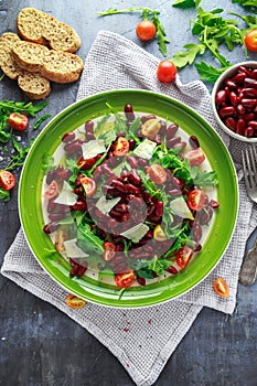 Red beans and wild rocket healthy salad with cherry tomatoes, sea salt flakes and parmesan shavings drizzled with olive