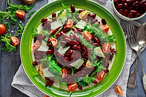 Red beans and wild rocket healthy salad with cherry tomatoes, sea salt flakes and parmesan shavings drizzled with olive