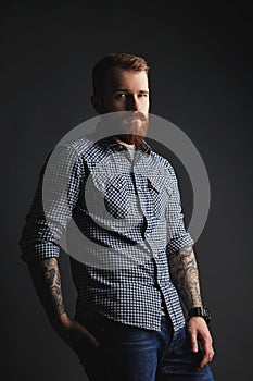 Red bearded man with tattoes studio portrait on dark background