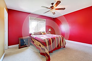 Red bedroom with bed and nighstand.
