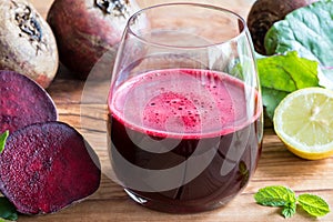 Red beet juice in a glass on a wooden background