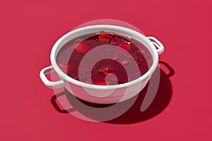 Red beet soup bowl on a red background. Bowl of the Ukrainian borscht