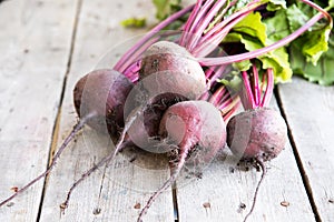 Red Beetroot with herbage green leaves on rustic background. Org