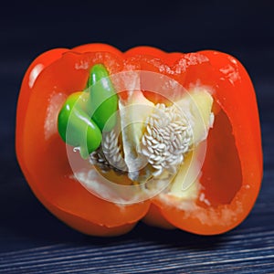 Red bell pepper on a black wooden background, cut in half