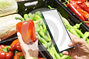 Red bell pepper vegetable in hand and smartphone  white