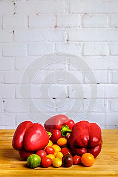 Red bell peppers and colorful cherry tomatoes with white brick wall background