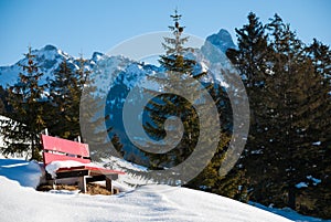 Red Bench in Snow, Background Austrian Alps Mountains