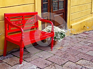 Red bench by the yellow wall in a small town in Slovakia