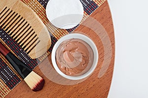 Red bentonite clay in the small white bowl, wooden hair brush, cotton pad and make-up brush. Diy facial or hair mask, body wrap
