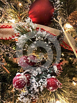 Red berries, pine cones, red ornaments, and lights on Christmas tree