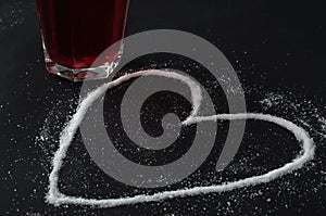 Red berries tea in glass, spilled sugar in shape of heart