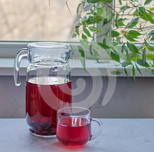 red berry compote against the background of a window and branch with green leaves