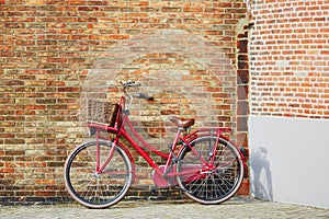 Red bicycle against brick wall in Brugge