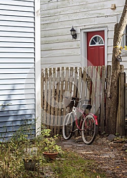 Red Bicycle Leaning Against an Old Fence on a Stone Path