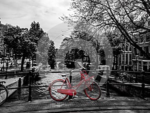 Red bicycle standin on a bridge, black and white photo
