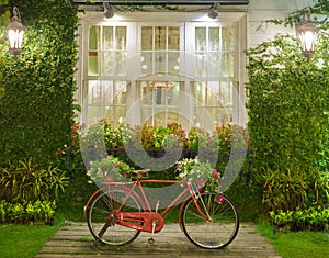 Red bicycle with white window and garden background